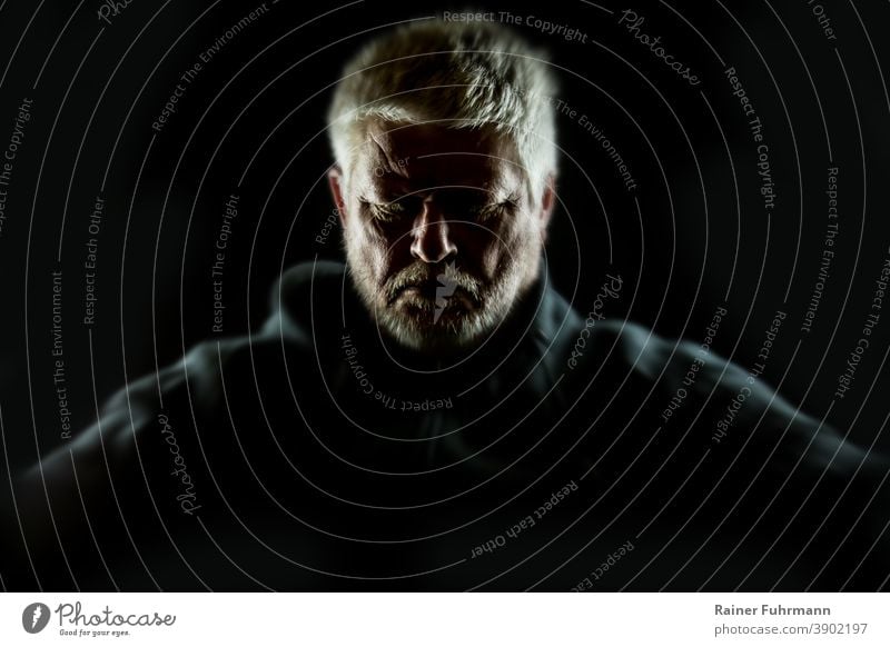 Portrait of a bearded man sitting alone in the darkness. Man portrait Lonely on one's own sad Loneliness depression Sadness unhappy person Think Concern Problem