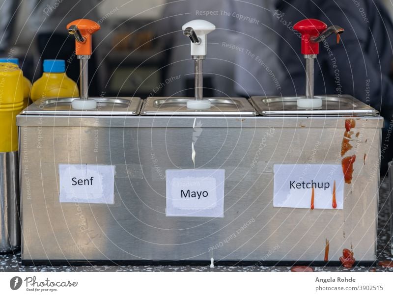 Dispenser for mustard, mayonnaise and ketchup at a sausage stand, with the German words for mustard, mayonnaise and ketchup Donor Mustard Mayonnaise Ketchup