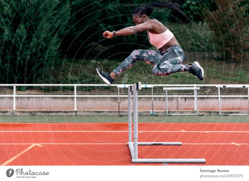 African-American athlete sprinter jumping a hurdle determined muscular afro american beginning african ambition motivation movement dynamic workout training