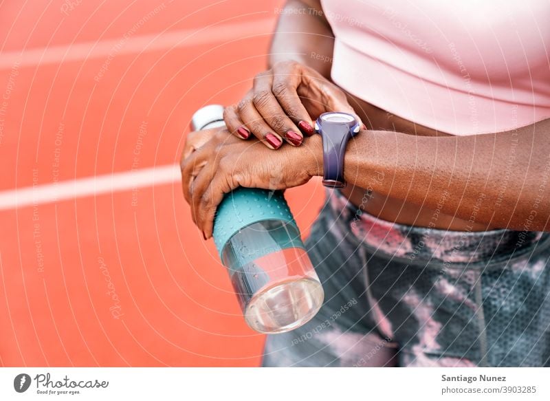 Athlete sprinter watching the clock with a bottle of water time start race training workout tie hydration athlete ethnic afro afroamerican track sportswear