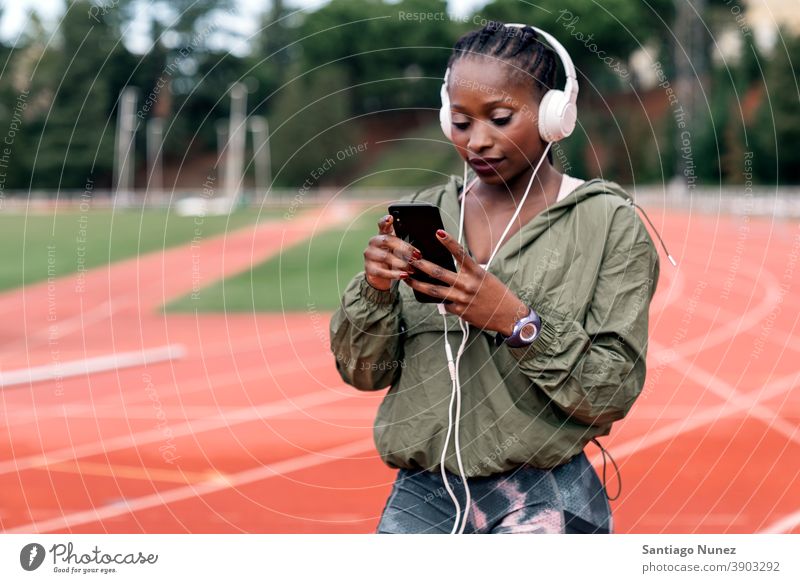 Athlete sprinter sitting listening to music smartphone afro concentration technology cell cellphone helmet mobile athlete ethnic afroamerican track train