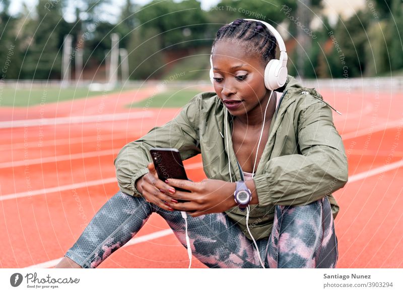 Athlete sprinter sitting listening to music smartphone afro concentration technology cell cellphone helmet mobile athlete ethnic afroamerican track train