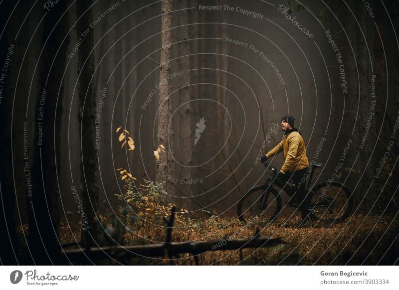 Young man taking a brake during biking through autumn forest action active activity adventure athlete bicycle bicycling bicyclist bike biker exercise extreme