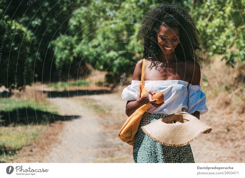 Happy black woman with fresh fruits in summer garden orange happy sunny nature enjoy cheerful young female african american ethnic smile spain cordoba travel