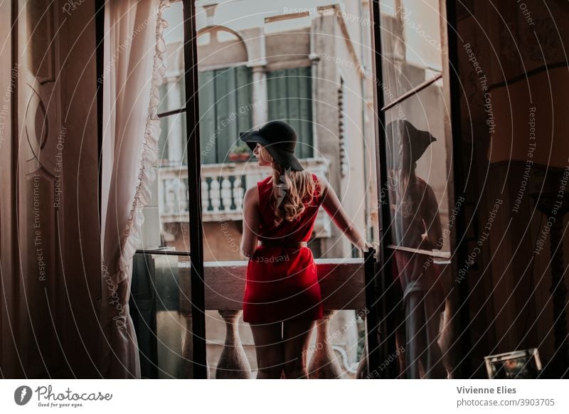 Woman With Hat Standing On A Balcony Looking Out vintage hat long hair blonde long-haired dress elegant beautiful woman curtains Silhouette Looking away balcony