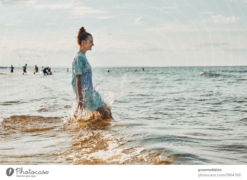 Girl enjoying sea jumping over waves spending a free time over sea on a beach during summer vacation excited positive sunset emotion carefree nature outdoors