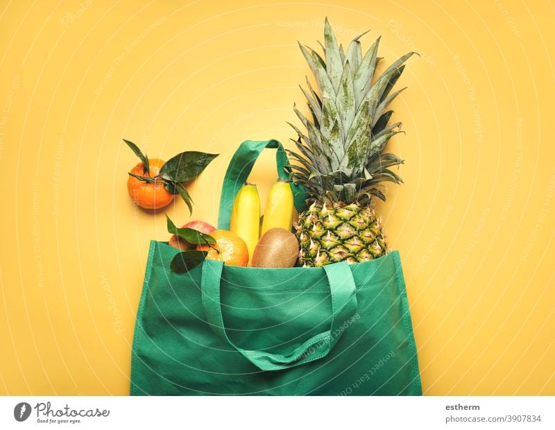 green shopping bag with different fruits,pineapple, bananas, oranges, kiwis and apples fruit store juice ingredients vegan products diet eco natural ecologic