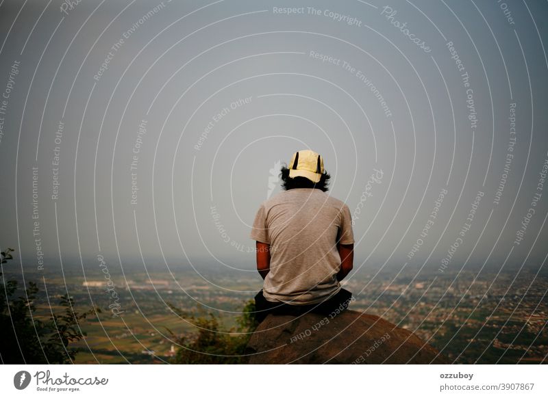 man sitting on the rock at mountain hill person landscape freedom peak hiking outdoor stone top looking extreme high sport young activity hiker journey leisure