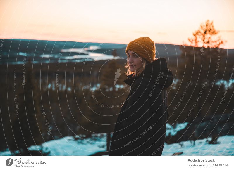 Traveling woman standing on hill in winter at sunset forest traveler vivid sundown outerwear wintertime female warm nature evergreen woods tranquil landscape