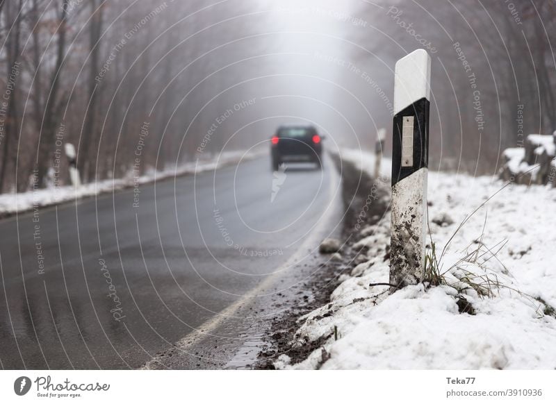 a car driving on a foggy winter forest street car on foggy street car on winter street evening car lights car in danger car in forest foggy winter street water