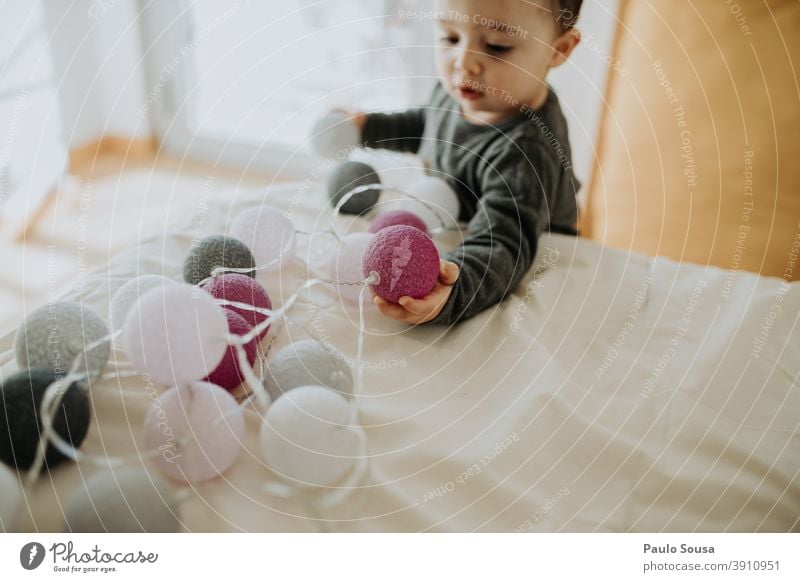 Toddler playing with christmas decorations 0-09 years at home authentic autumn casual caucasian child color curiosity enjoyment explore happy Christmas & Advent