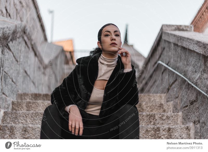 Hot stylish female wearing black clothes and sitting on a stone staircase. woman pretty afro attractive ethnicity real woman human being copy space winter