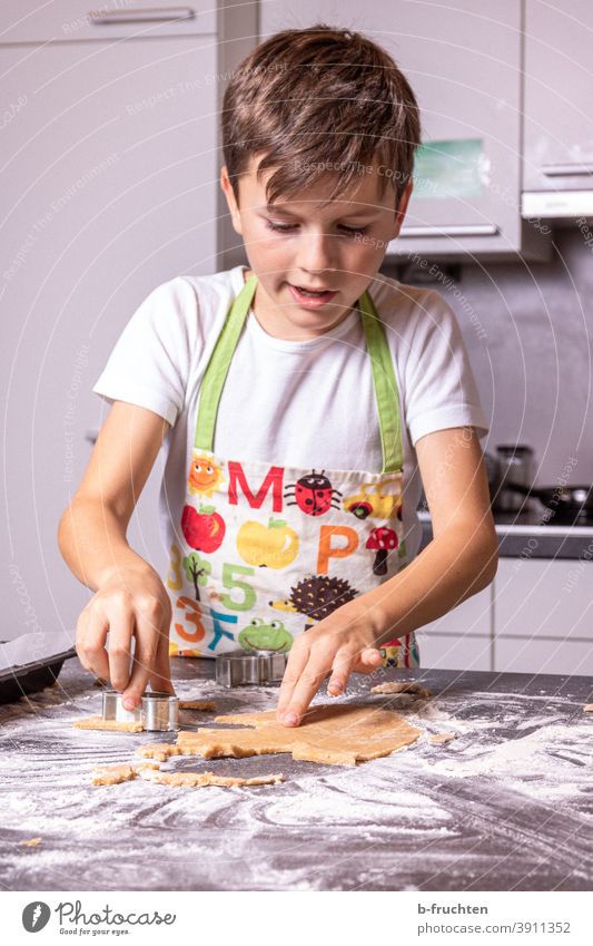 Cutting out a child while cutting cookies Cookie outdo sb. Child Kitchen Table dough Flour Baking cookie dough Christmas & Advent cookie cutter cut out cookies