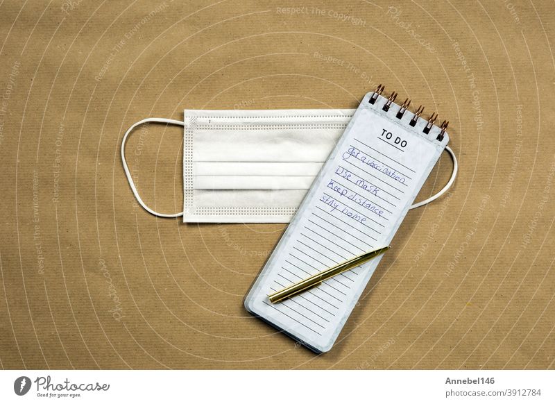 White medical masks and Notepad with measures against Coronavirus on brown paper background, COVID-19 concept modern design top view, copy space safety notebook