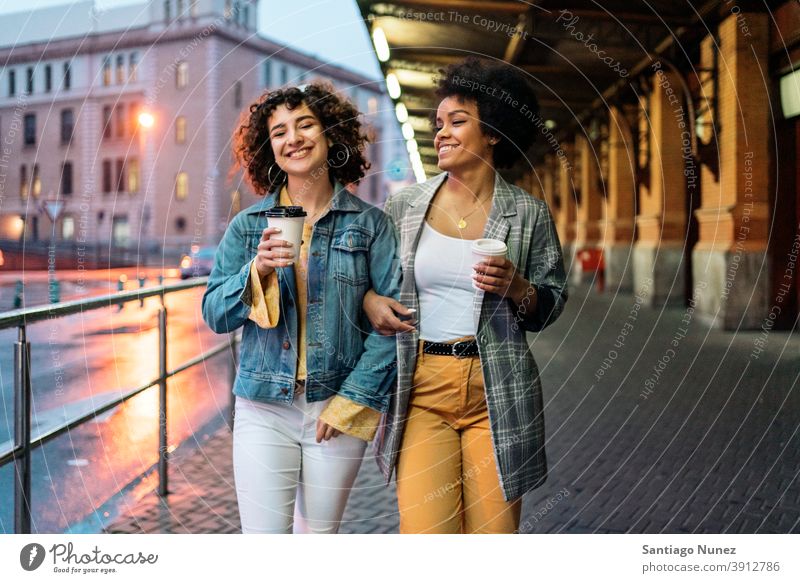 Afro Girl and Friend in Street cup of coffee walking street friends drinking women multi-ethnic afro girl caucasian portrait having fun front view friendship