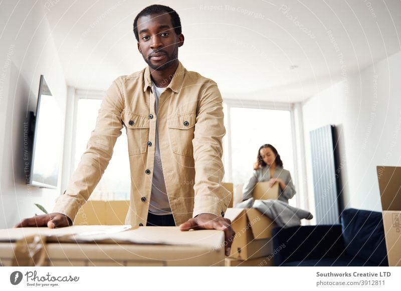 Portrait Of Young Couple In New Home Unpacking Removal Boxes In Lounge Together couple young couple house buying unpacking boxes home new home first home