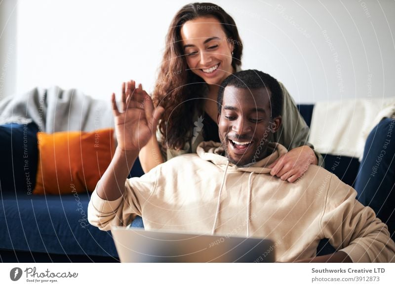 Relaxed Young Couple At Home Sitting On Sofa Making Video Call On Laptop Computer couple young couple at home laptop computer video call video chat