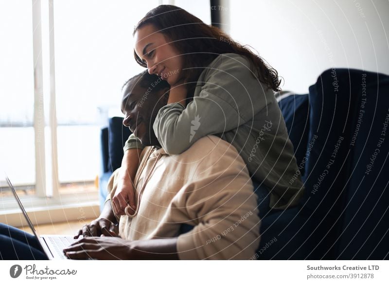 Relaxed Young Couple At Home Sitting On Sofa Browsing Internet On Laptop Computer couple young couple at home laptop computer browsing shopping buying booking