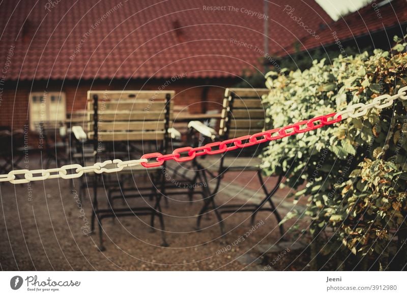 With a red and white chain cordoned off and closed outdoor area of a restaurant in the Corona pandemic in the lockdown | corona thoughts Closed Restaurant Café