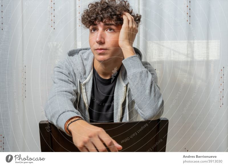 Attractive young man with curly hair wearing gray sweatshirt posing on white curtains background cheerful casual smile male adult handsome happy attractive