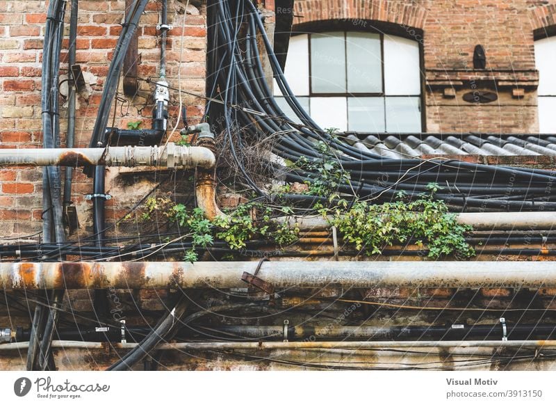 Rusty pipes, cabling and weeds on the roof of an old factory urban industrial bricks building cables weathered structure architecture front rusty aged facade