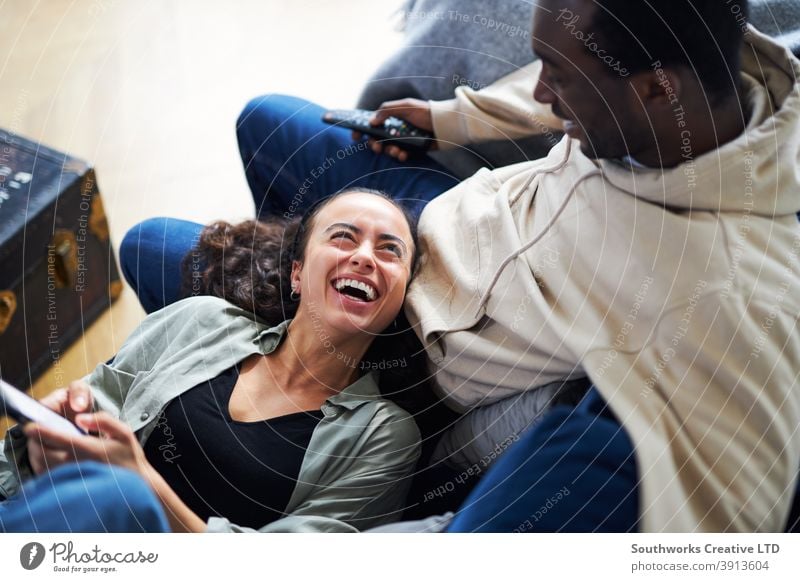 Overhead shot of relaxed young couple at home on sofa watching TV and checking cell phone Couple Sit Sofa Lounge TV set Television Mobile Cellphone technology