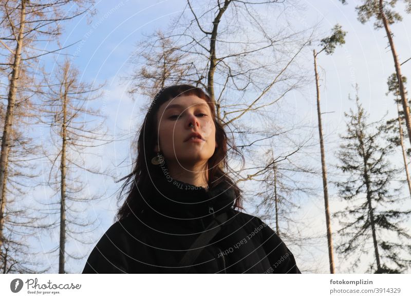 Portrait of a young woman looking down under bare treetops Face of a woman portrait Woman Identity Long-haired feminine Self-confidence Self-confident