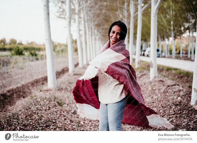 portrait of hispanic mid adult woman outdoors holding wrapped in blanket. Autumn season autumn afro woman latin sunset nature hat smile happy joy young