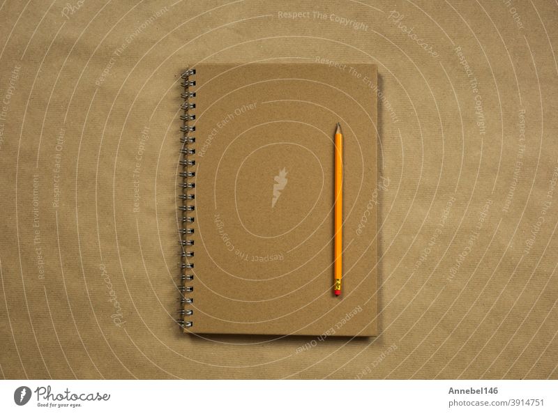 Brown notebook and classic pencil on brown plain paper background texture, copy space or space for text, business or education concept top view modern retro design