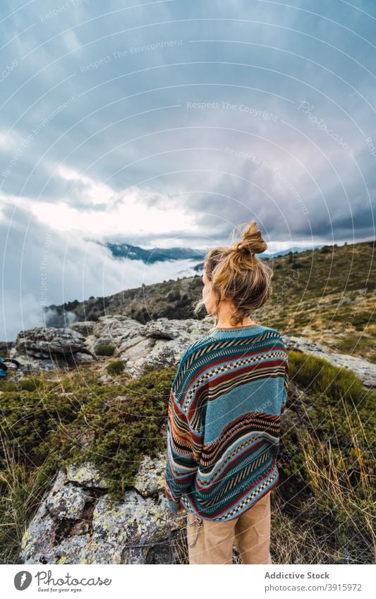 Traveling woman enjoying freedom in mountains traveler hiker carefree rock highland top female vacation relax holiday landscape rest stone tourist sky explore