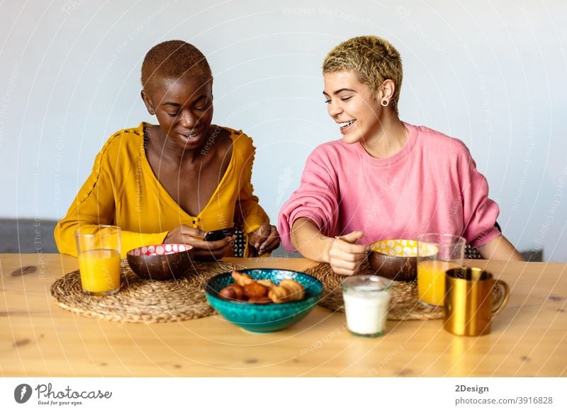 Two young women couple, best friends sitting in cafe, eating breakfast and drinking coffee, using smartphone. friendship domestic life together smiling