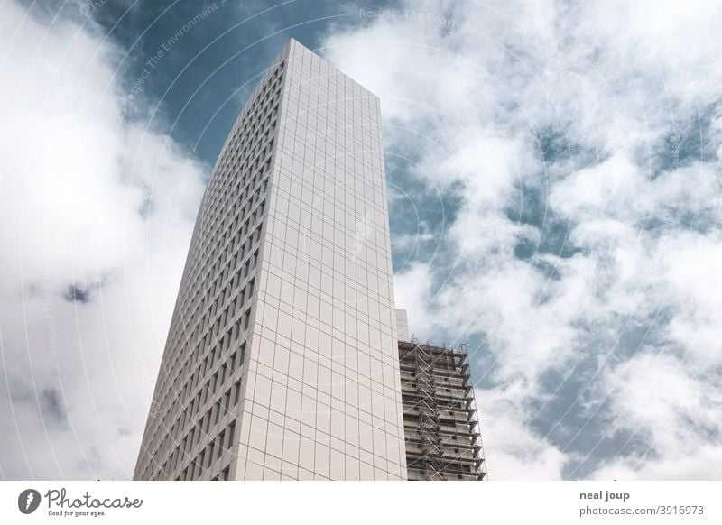 White office tower with scaffolding from frog perspective in front of blue sky Architecture High-rise Office building Facade Town outline Construction site