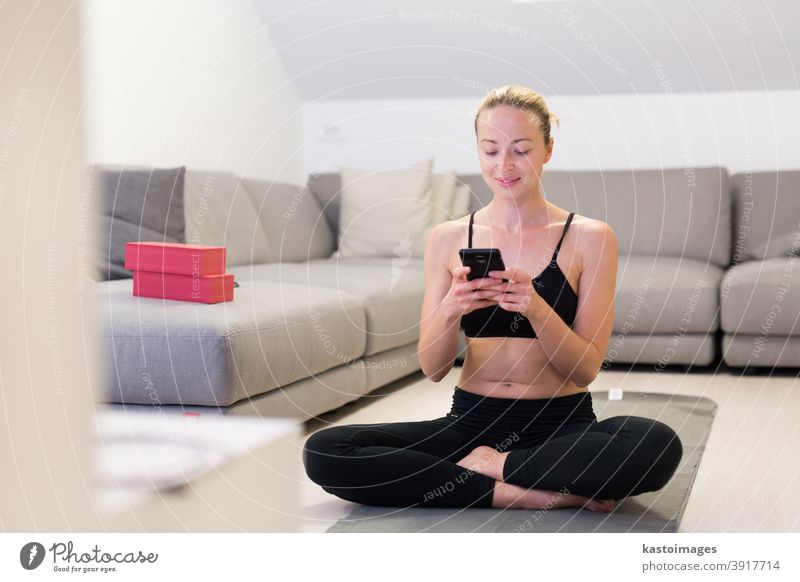 Beautiful blonde woman doing home workout indoors. Woman practice yoga at home. Fit girl using workout tutorials for healthy active lifestyle. Woman using quarantine for home workouts.