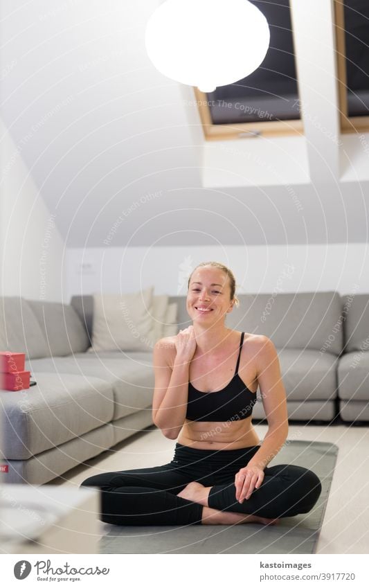 Beautiful blonde woman doing home workout indoors. Woman practice yoga at home. Fit girl using workout tutorials for healthy active lifestyle. Woman using quarantine for home workouts.