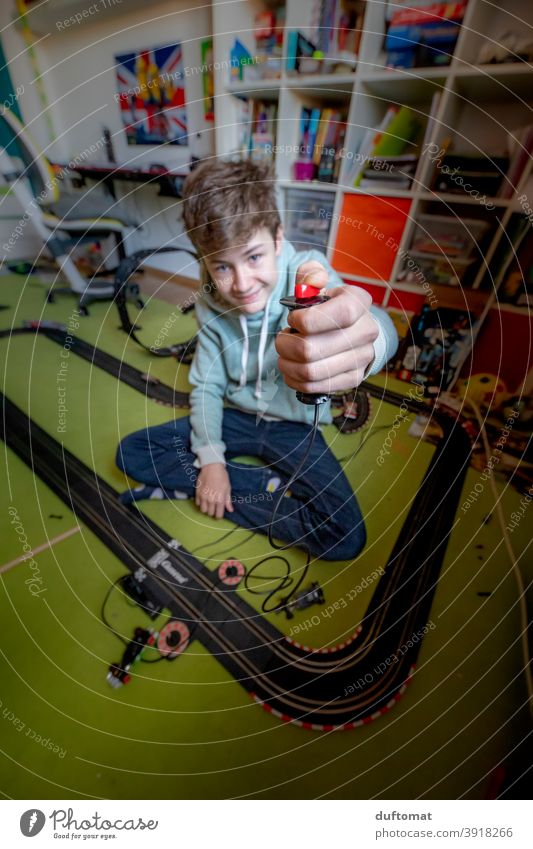 Boy presses remote control of a Carrera track in the children's room Model racecourse Children's room Boy (child) car Running Playing Joy Infancy Happiness