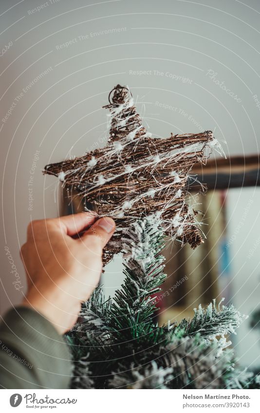 Close up of a man's hand hanging the christmas star on the tree. christmas ornament christmas decoration ornate elegant isolated festive release garland