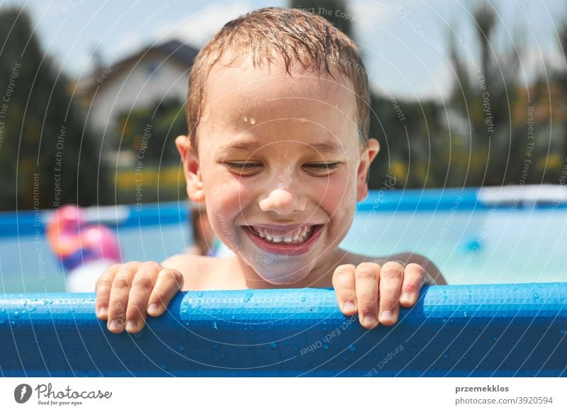 Portrait of happy smiling boy playing in a pool having fun on a summer sunny day authentic backyard childhood children family garden happiness joy kid laughing