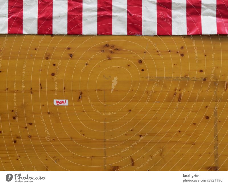 Back of a market stall with striped tarpaulin and small sticker Market stall stickers Striped Reddish white Wood boards Knotholes Colour photo Brown White