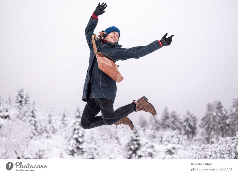 A young woman is happy about the first snow and makes a jump in the air Snow Winter Joy Happy fortunate Ballet Cold