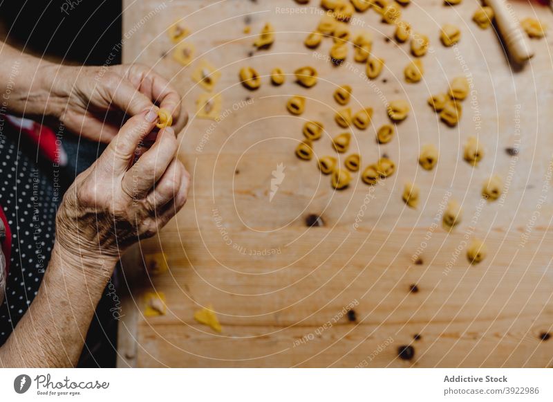 Crop aged woman preparing tortellini in domestic kitchen cook italian food homemade tradition dumpling prepare female dough raw ingredient table italian cuisine