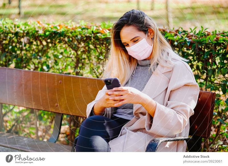 Cheerful woman in mask using smartphone in park coronavirus new normal protect speak cheerful female mobile phone device gadget call covid sit epidemic covid 19