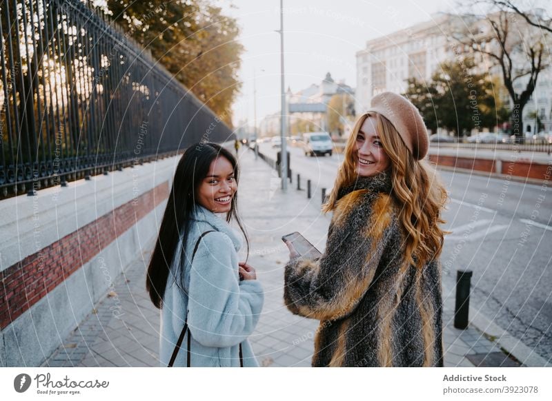 Cheerful multiethnic women walking along street stroll city friend friendship cheerful weekend enjoy autumn female multiracial diverse smile happy optimist