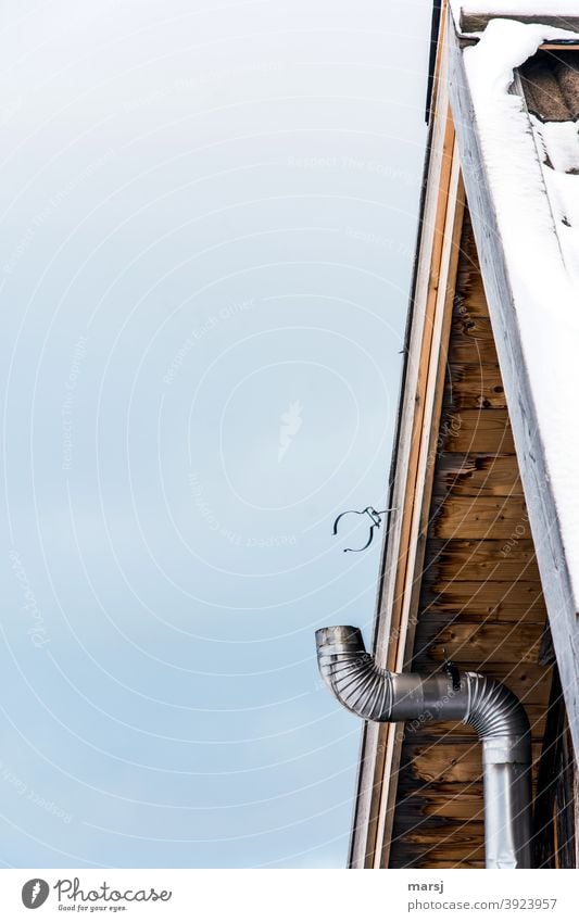 The pipe clamp at the gable of a simple hut waits for the completion of the stovepipe or at least for a meaningful use Stovepipe Heating pipe pipe clip Ice