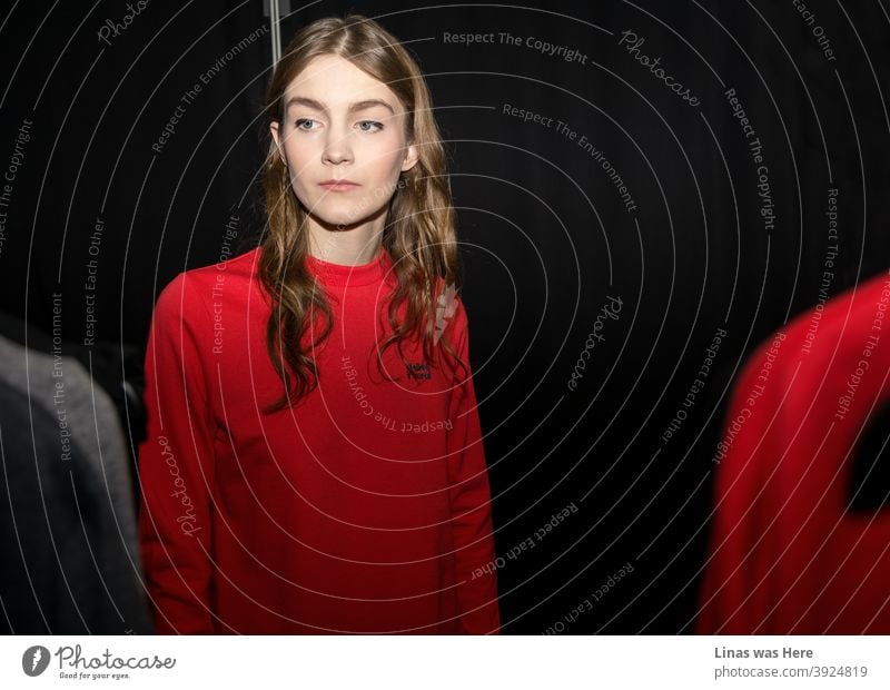 A short break during a photo shoot in a backstage where models are getting ready. A beautiful brunette girl is preparing for a model test while wearing a comfy red sweater.