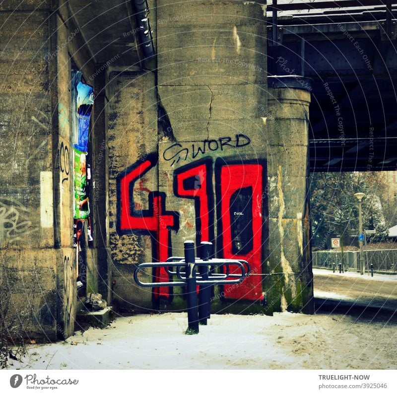 Through wild Babelsberg in winter with dirty snow, a railway underpass, bold blood red graffiti numbers 490 and S word written black on grey concrete pillar, empty bike stand, street, garden fence, lantern