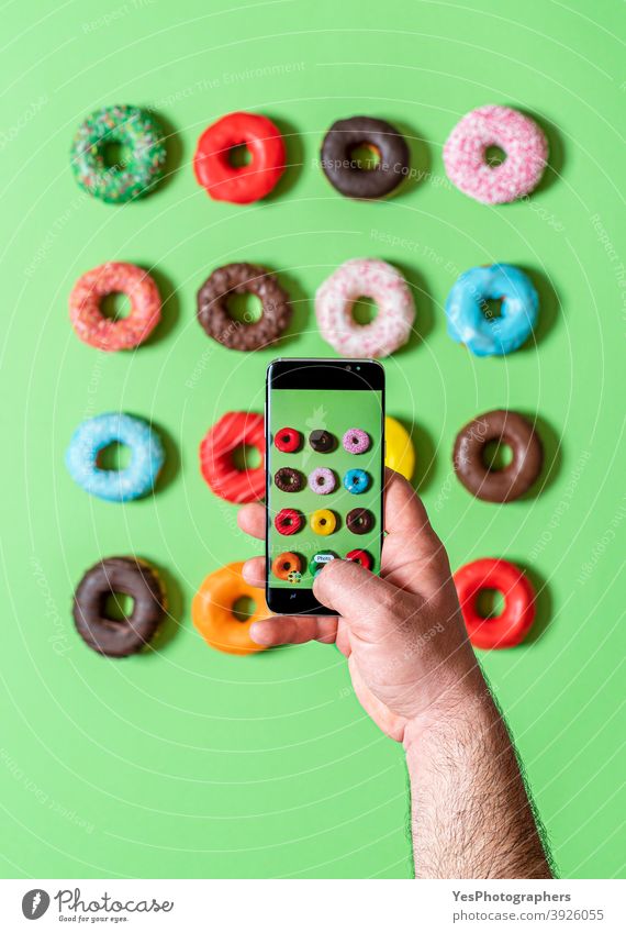 Taking photos of donuts with the smartphone. Photographing food top view. above view aligned assorted background baked bakery blue breakfast cake