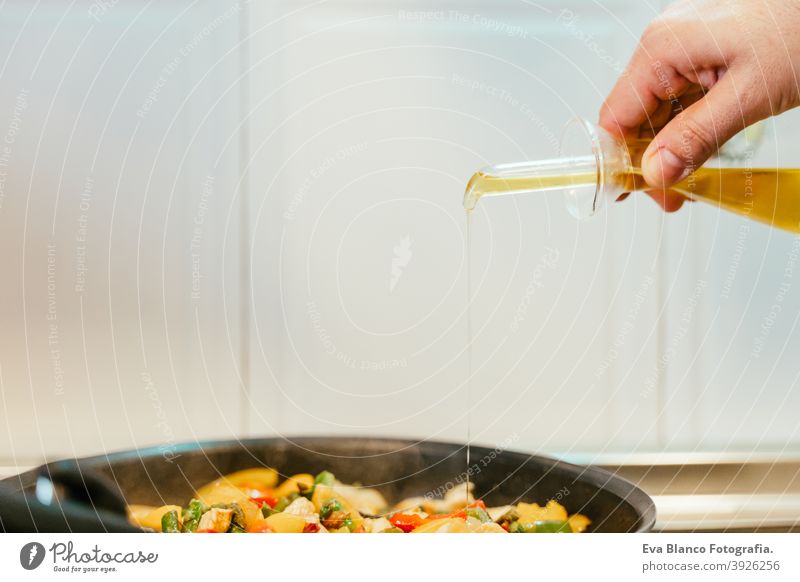 unrecognizable man preparing vegetables food in pan. Adding olive oil. Healthy food kitchen pepper colorful healthy carrot cabbage cut spoon vegan red sauteed