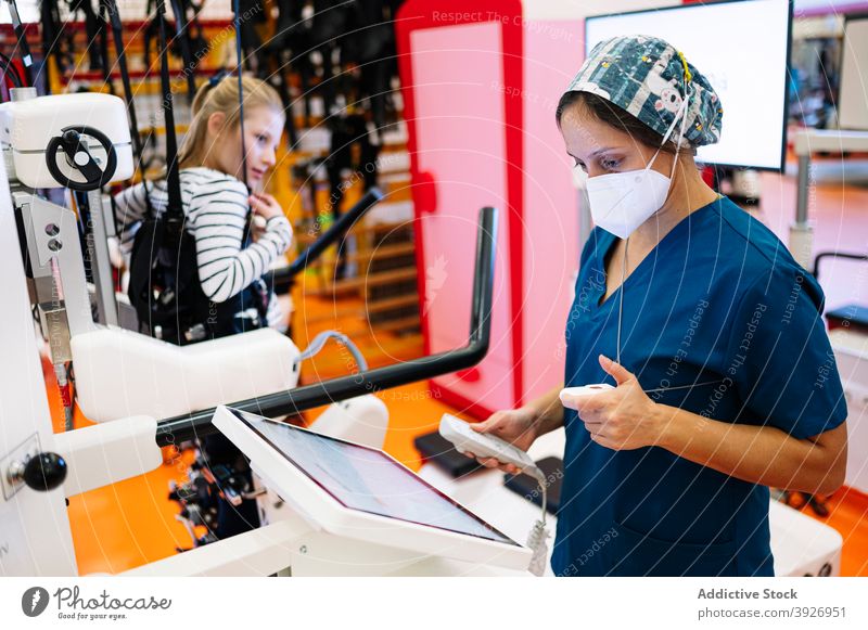 Physiotherapist checking equipment before training with disabled kid rehabilitation physiotherapy prepare device electronic using development activity child