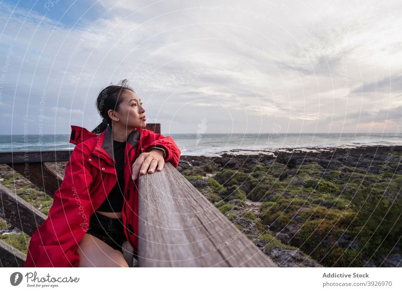 Pensive woman sitting on sea coast shore pensive alone thoughtful ocean rest contemplate dream young asian female ethnic seashore freedom lonely solitude relax