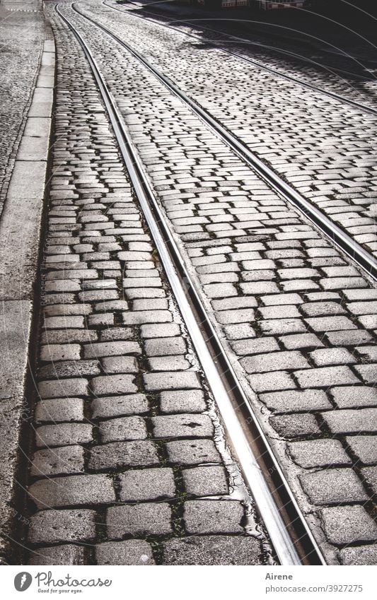 always on the rails Street Cobblestones tram tracks Right ahead straight Deserted Gray paved sunny Pedestrian precinct Paving stone railway tracks